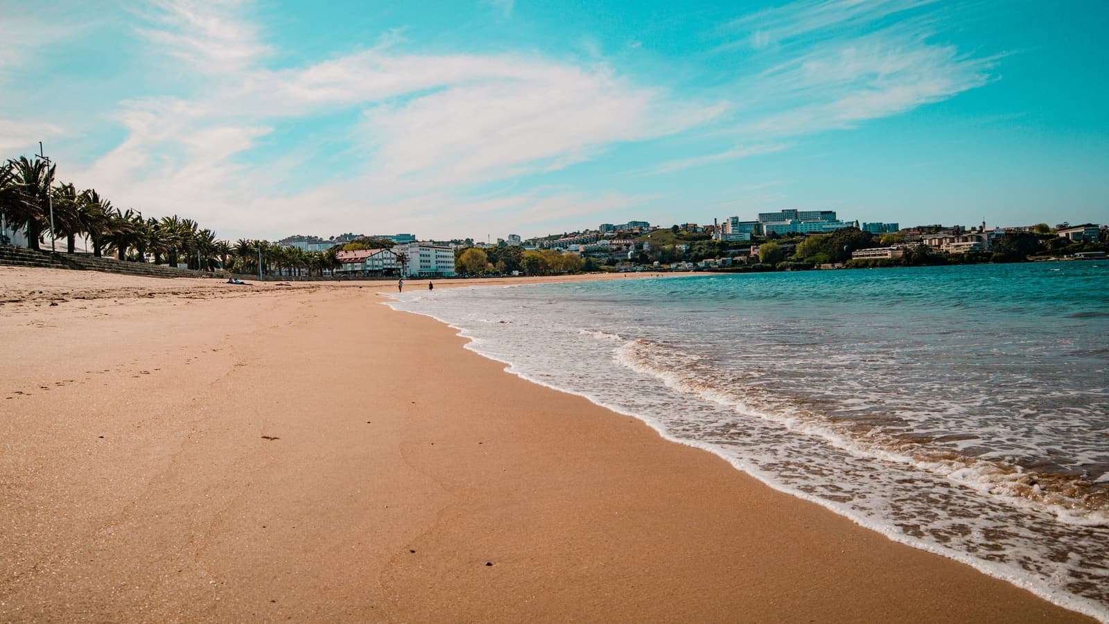 Playa de arena en Oleiros con viviendas al fondo