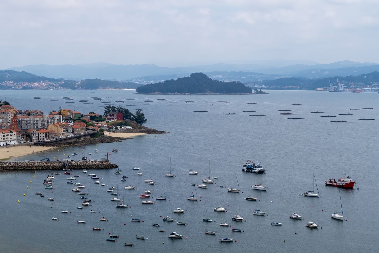 Ría gallega con barcos fondeados frente al pueblo